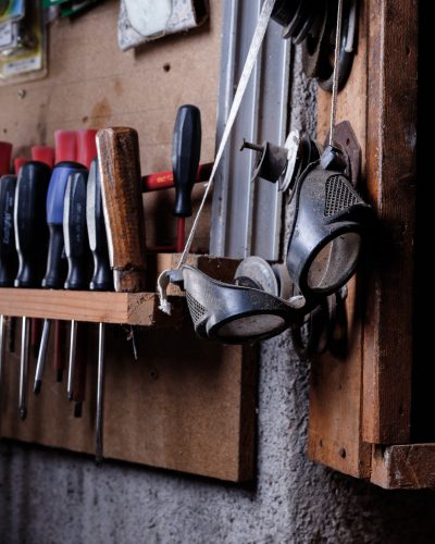 Vieilles lunettes de protection suspendues dans un atelier, témoignage d’un savoir-faire artisanal.
